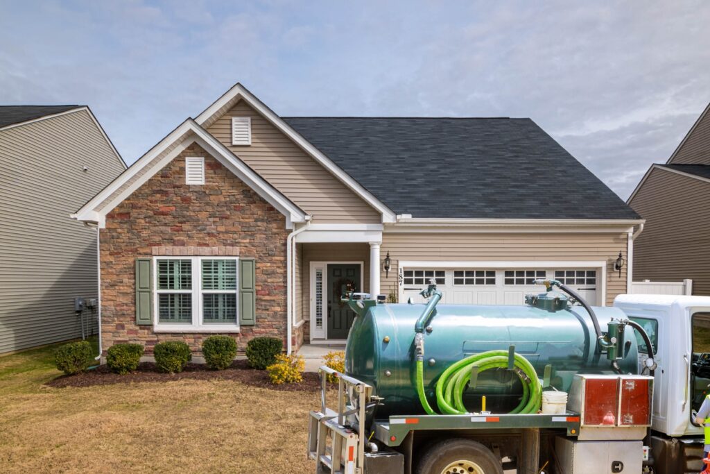 A truck with a green hose parked in front of a home.