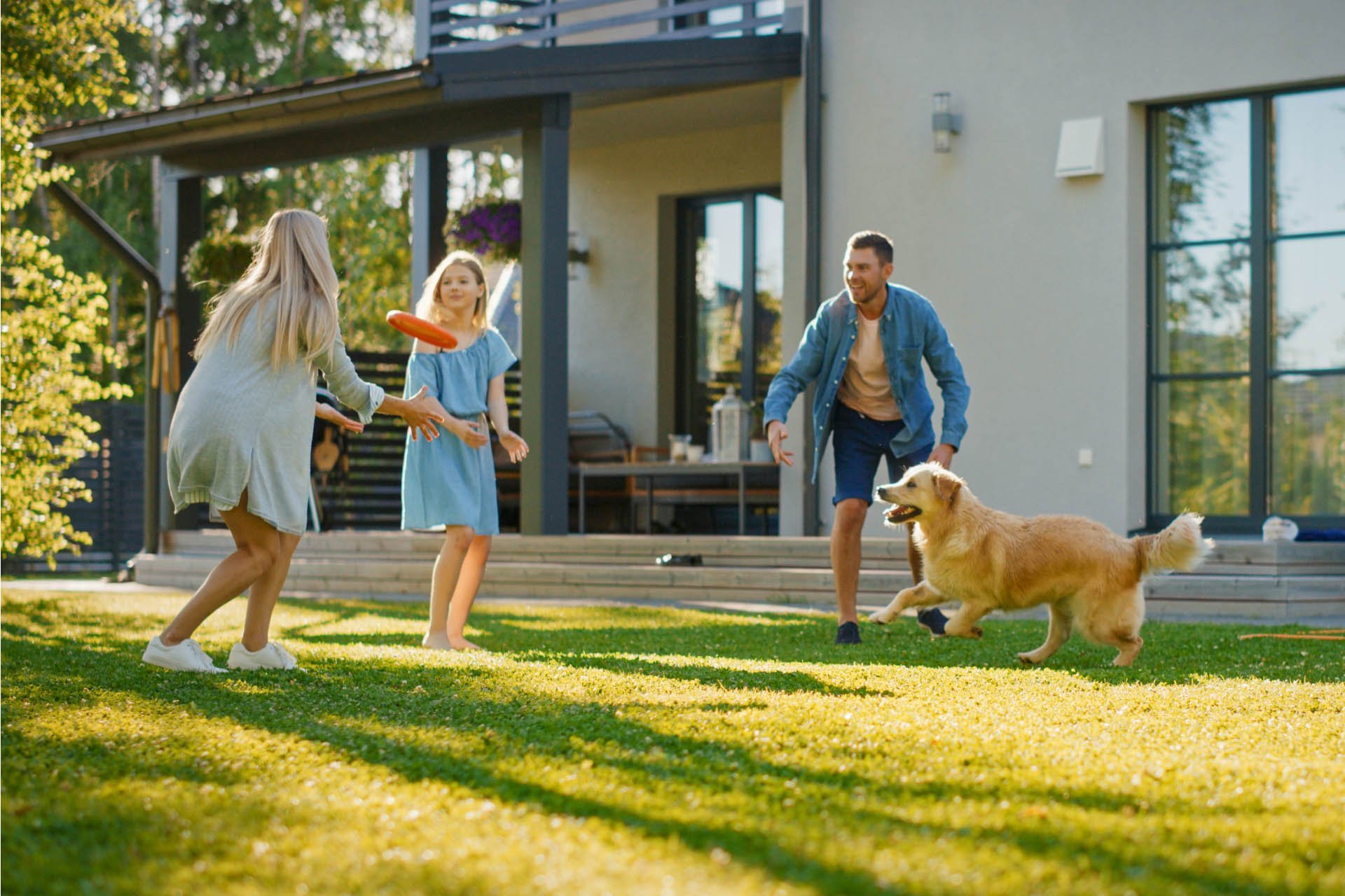 A family playing with a dog outside their home.