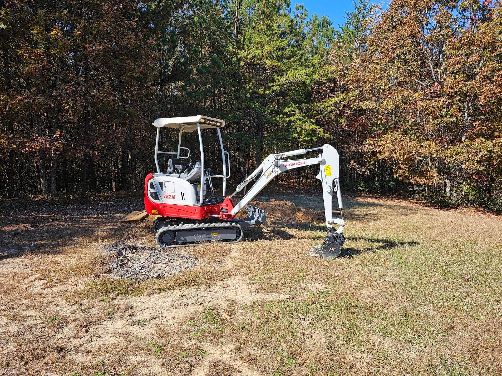A red and white excavator in a field.