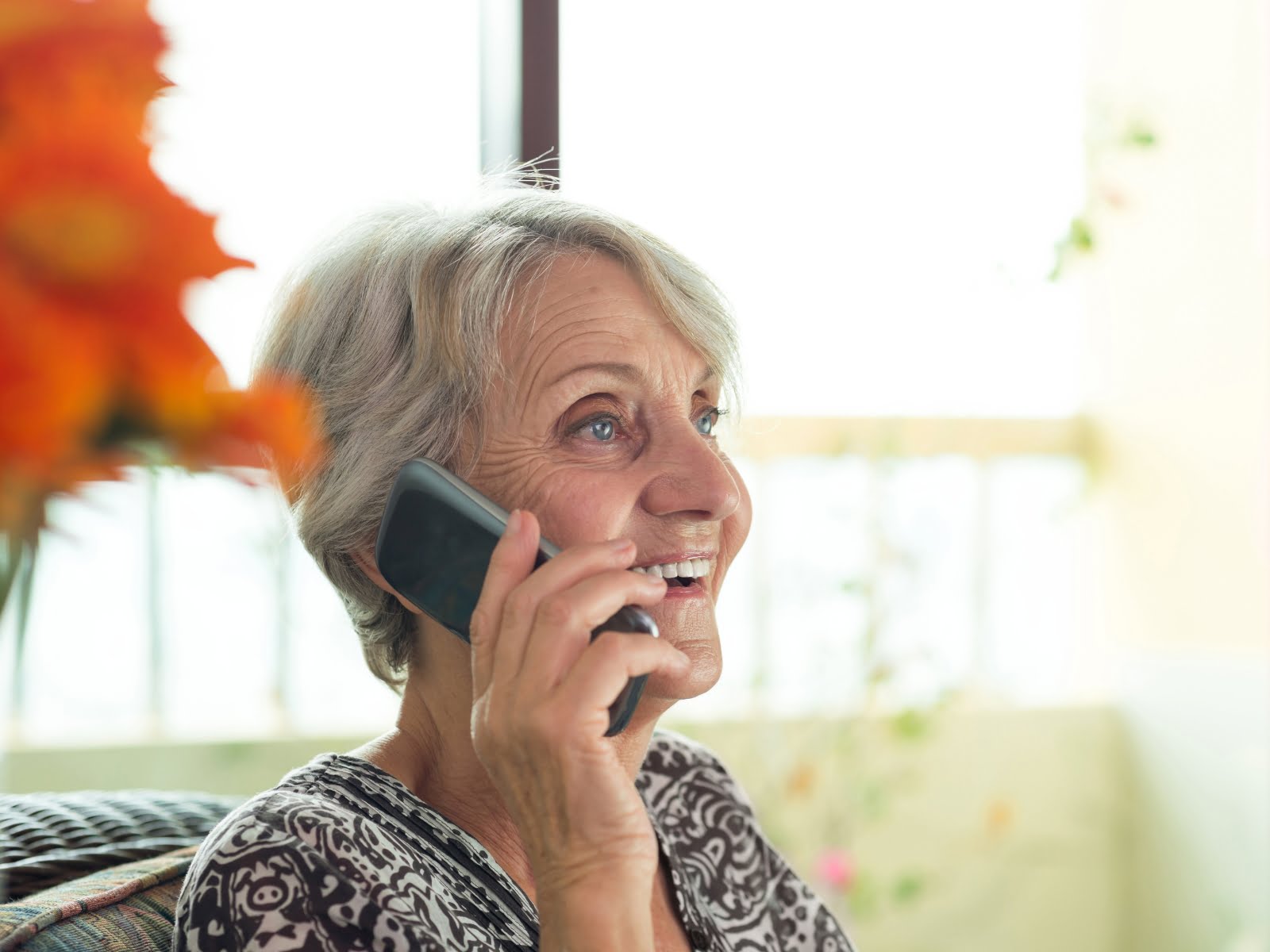 An older woman contacting someone on a cell phone.