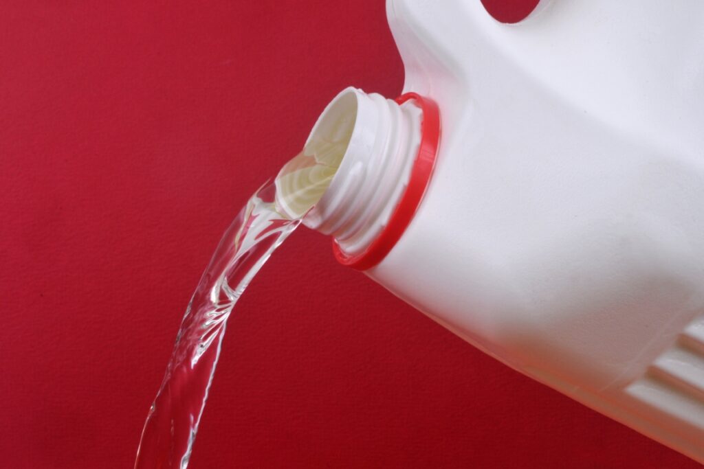 A white jug of water is being poured into a red background, debunking septic tank myths.