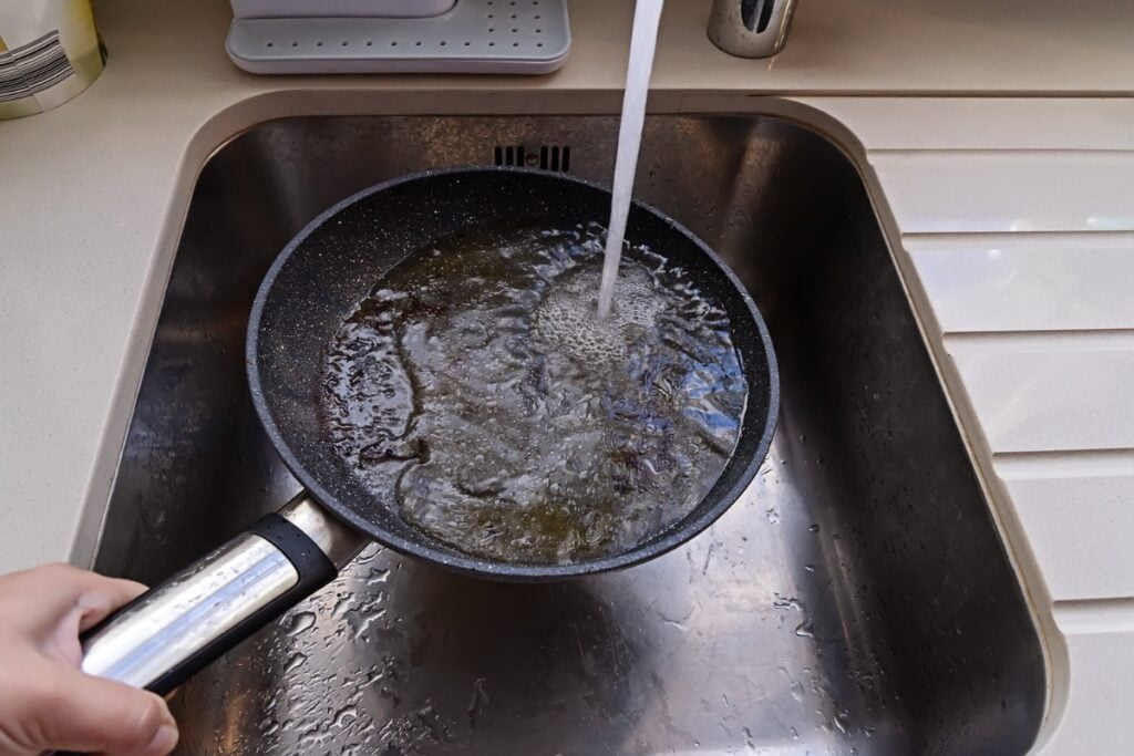 A person debunking septic tank myths while pouring water into a pan in a kitchen sink.