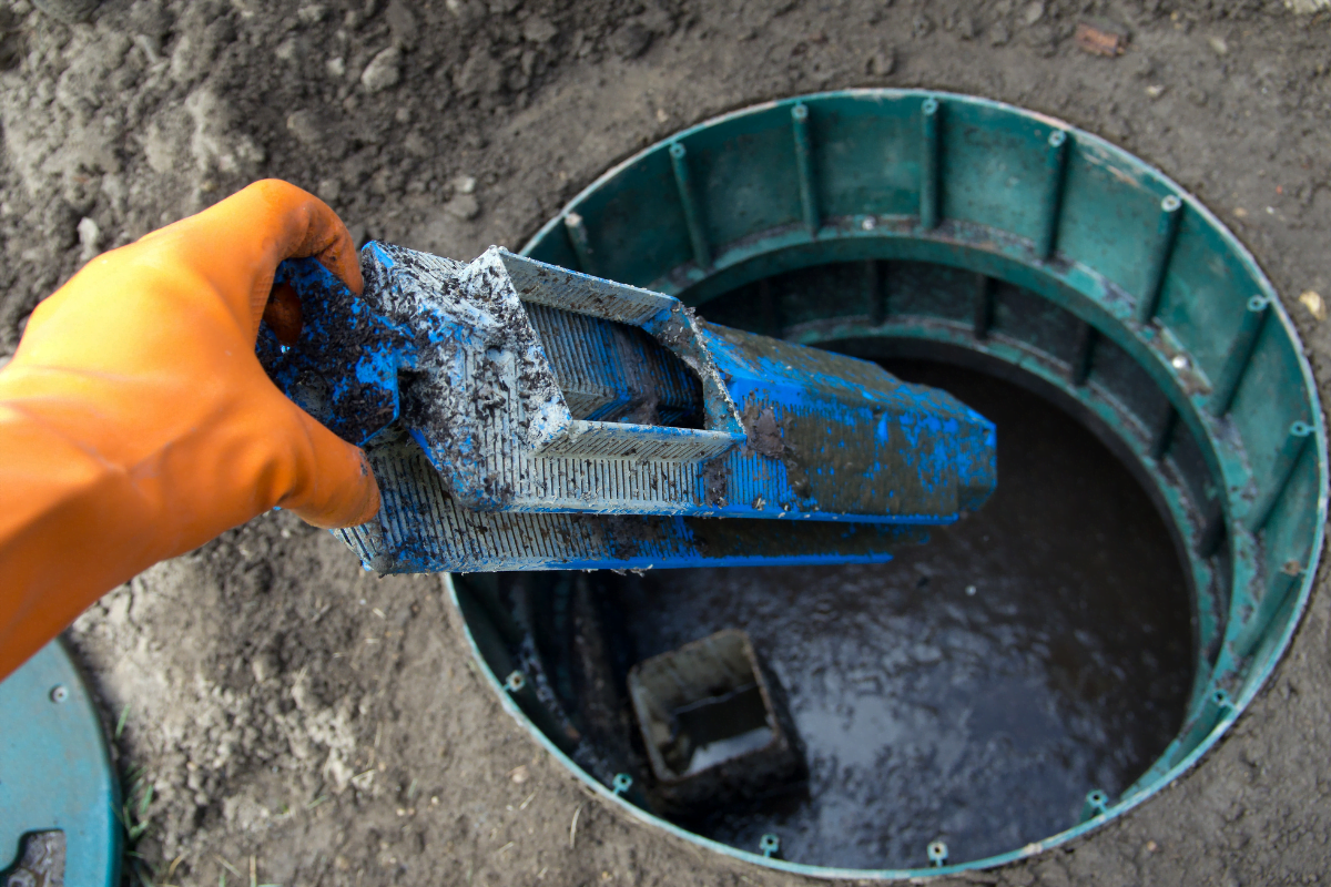 A person is holding a blue pipe in a Mableton septic tank.