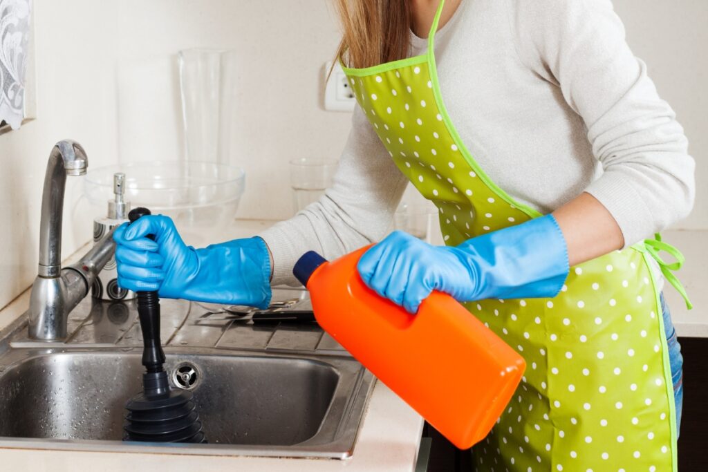 A woman in an orange apron cleaning a kitchen sink while dispelling septic tank myths.