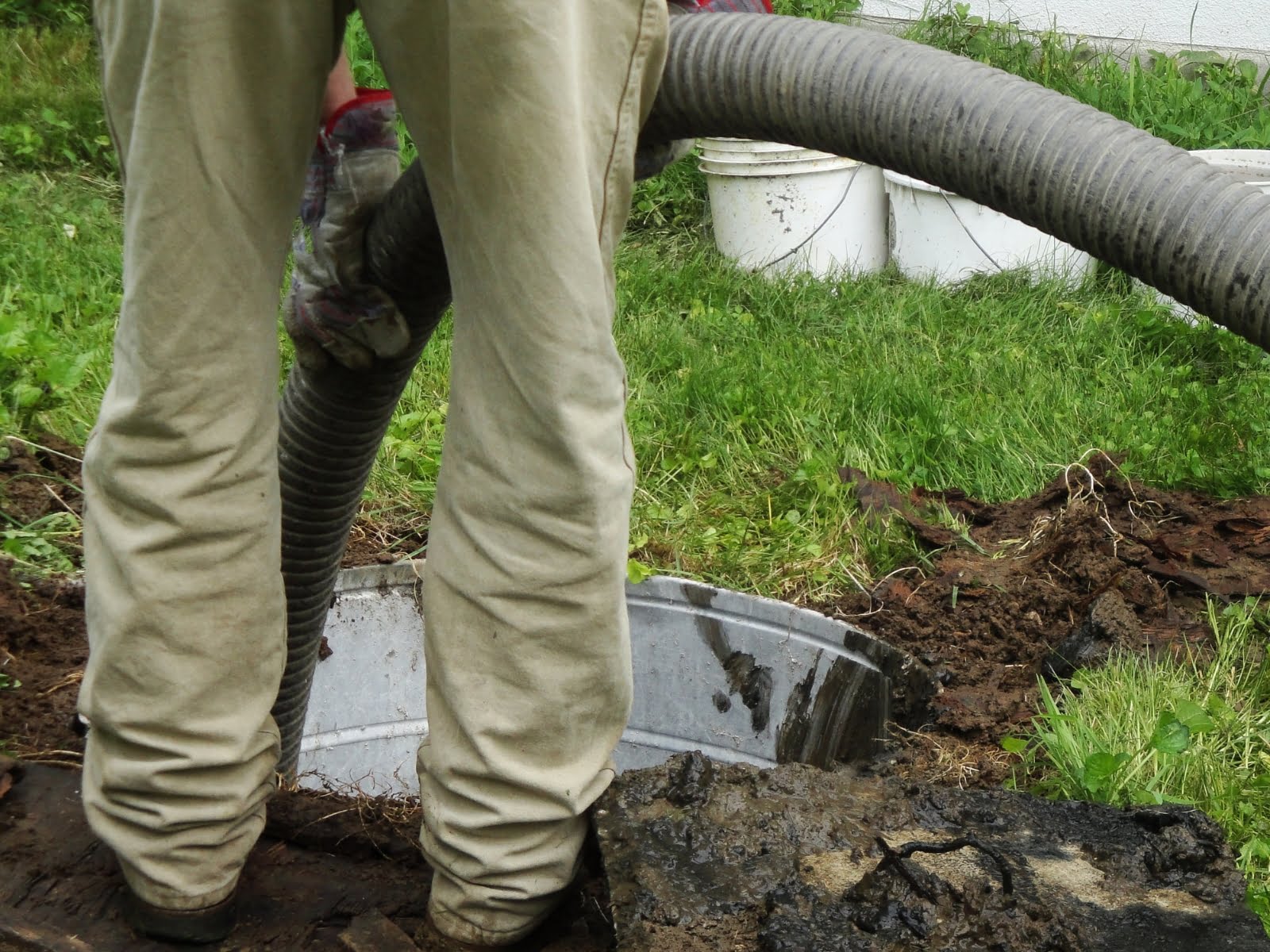 A man performing septic tank maintenance in a yard.