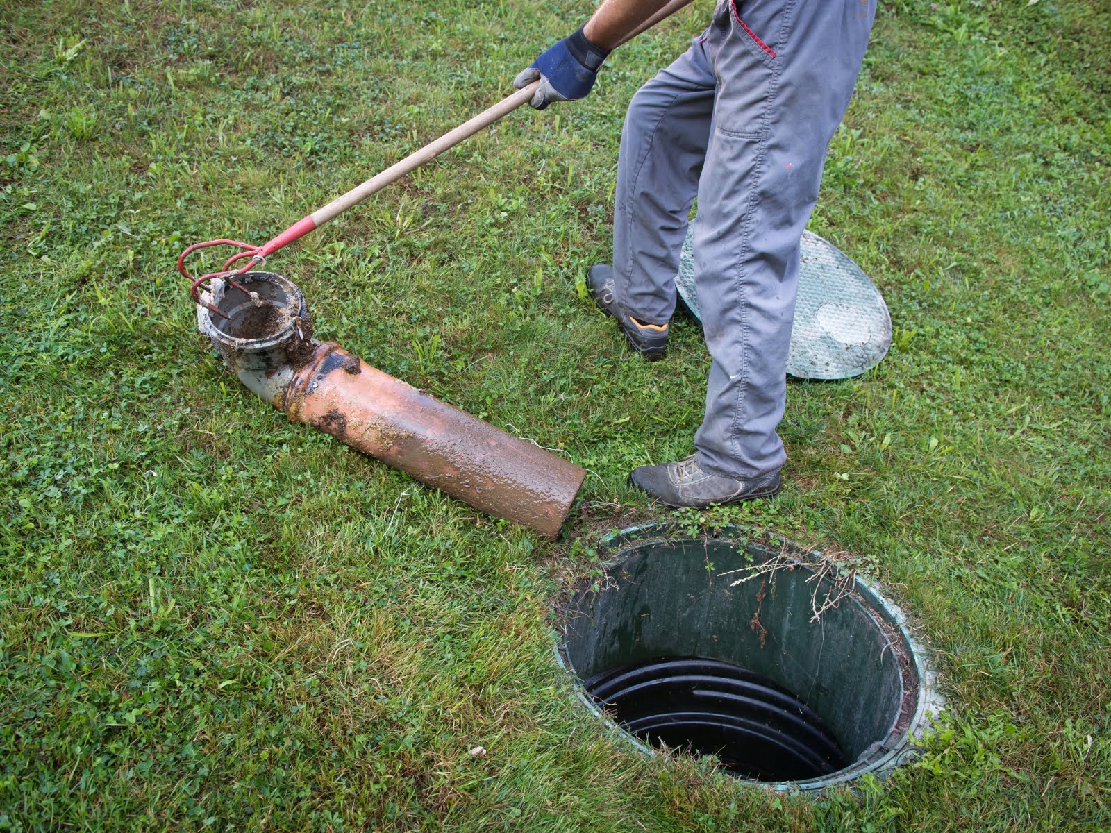 A man inspecting a septic pipe during tank tank repairs.