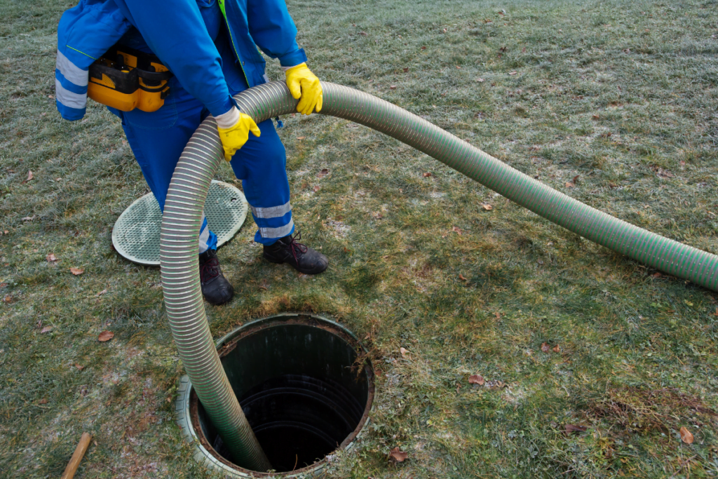 A man is using a hose in a grassy area as part of septic maintenance,