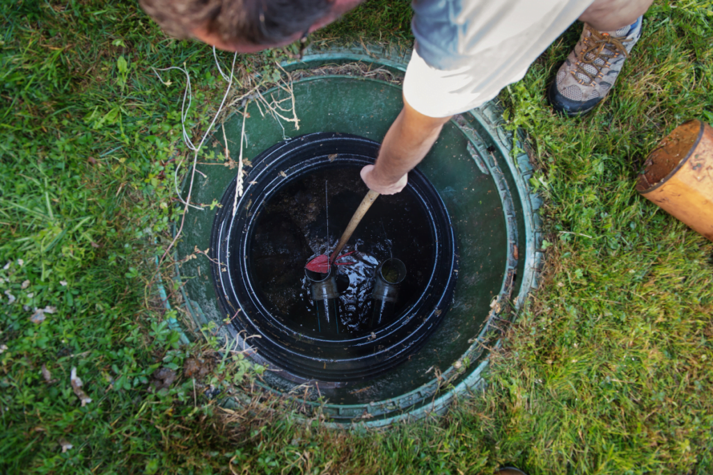A man performing septic system care by cleaning the hole in the ground.