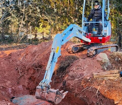 A man operating a construction vehicle for septic tank installation.