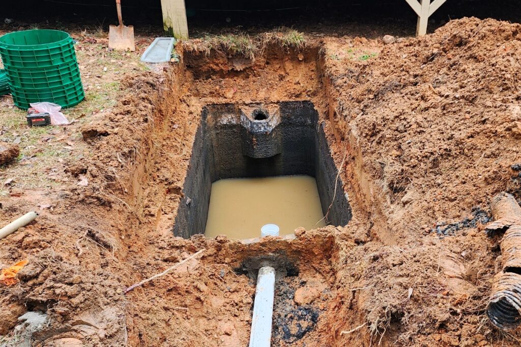 A hole in the ground with a pipe in it that complies with septic system regulations.