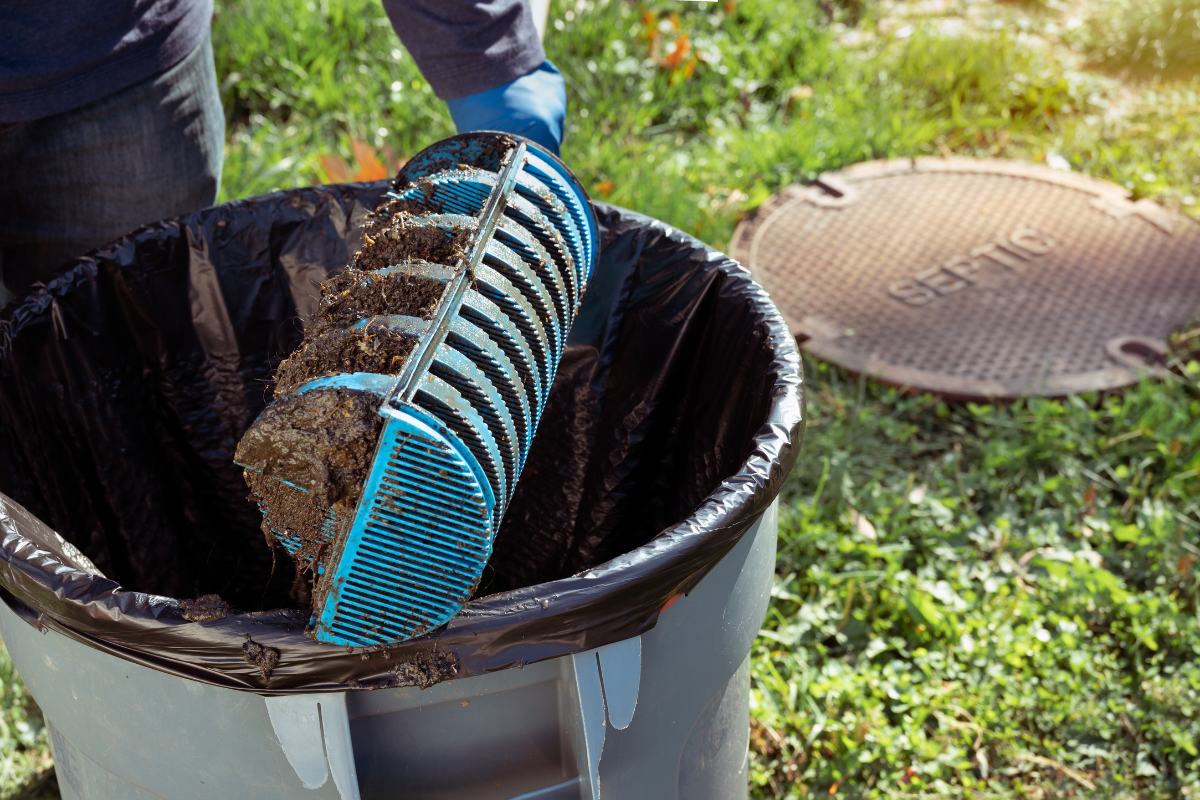 Person disposing of a shovel-full of dirt into a garbage bin during the installation of septic systems.