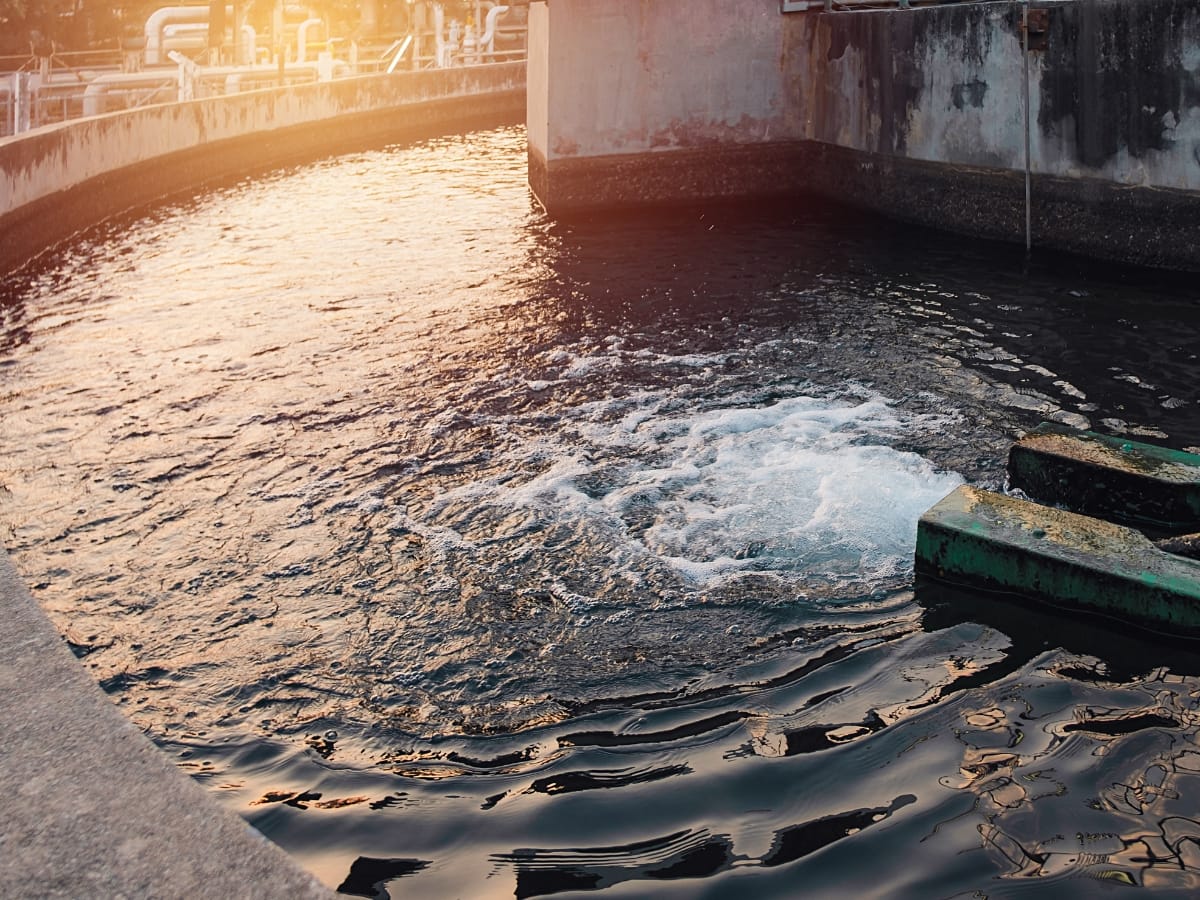 A circular water treatment basin with churning water and equipment at sunset exemplifies sustainable wastewater management, showcasing innovation in harmony with nature.