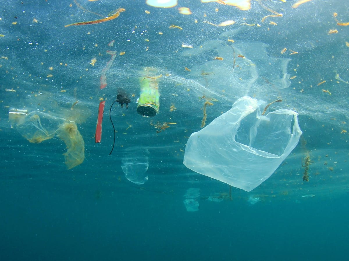 Underwater view of plastic pollution, including bags, bottles, and various debris floating near the ocean surface—a stark reminder of the urgent need for sustainable wastewater management to protect our marine environments.