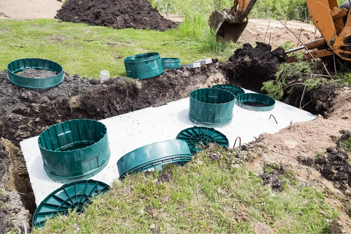 How Much Does a Septic Tank Cost? Factors Affecting Prices 2 Groundwork for a septic tank installation is in progress, with green circular components arranged on a concrete slab. Considering the septic tank cost, every detail is meticulously planned to ensure efficiency and durability.