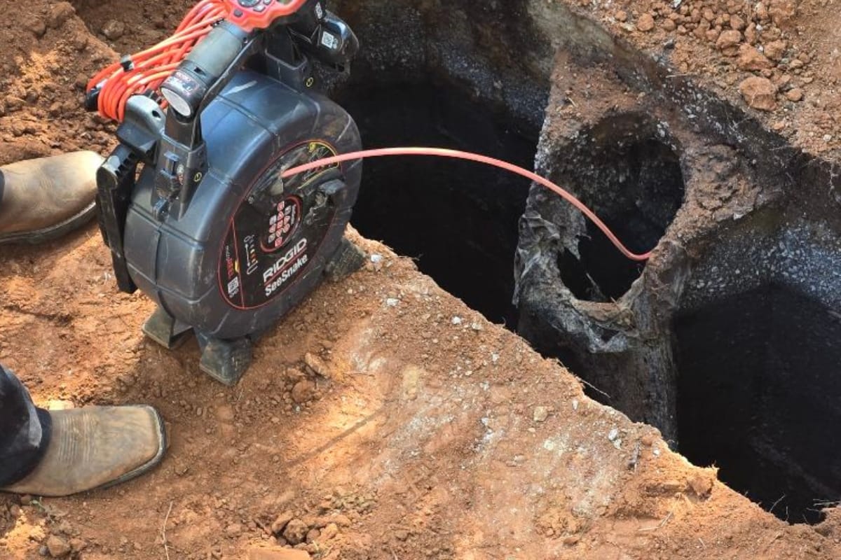 Septic System Inspection Process in Marietta, GA: What to Expect 1 A person uses a sewer inspection camera to examine underground pipes exposed in a dirt excavation site during a septic system inspection.