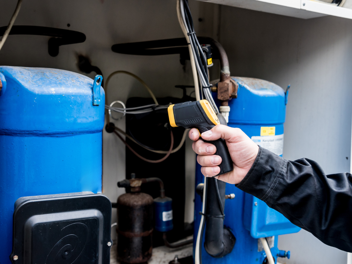 A person uses a handheld infrared thermometer to measure the temperature of equipment in an industrial or mechanical setting, a technique also valuable during real estate inspections to ensure systems are functioning safely and efficiently.