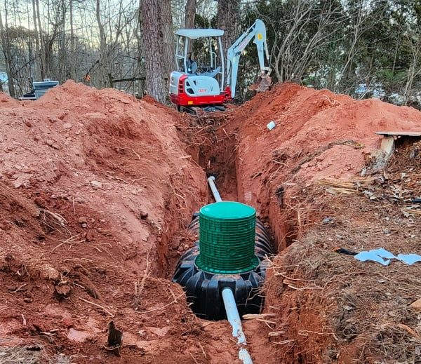 A man from smart septic pros tank company is digging a hole in the ground with a shovel.