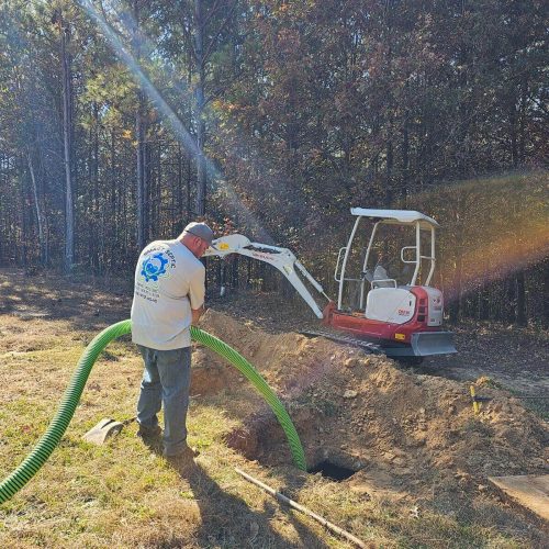 A man working on a tractor with a green hose.