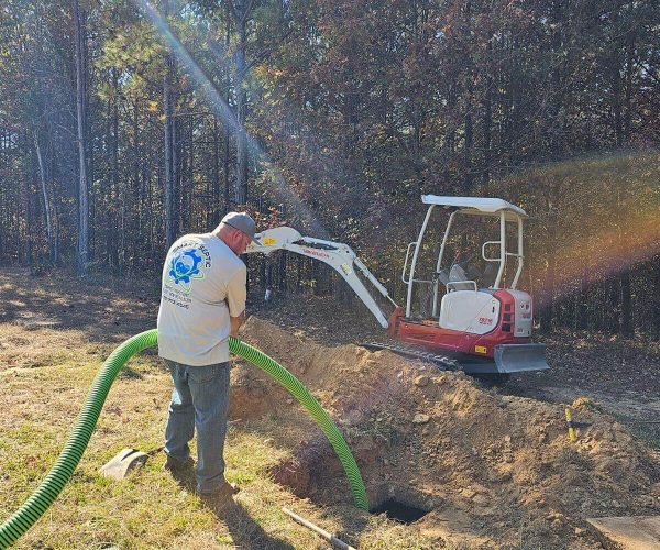 A man working on a tractor with a green hose.