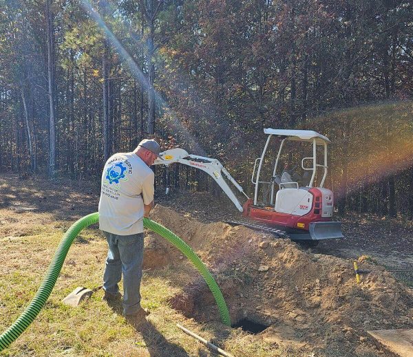 A man working on a tractor with a green hose.