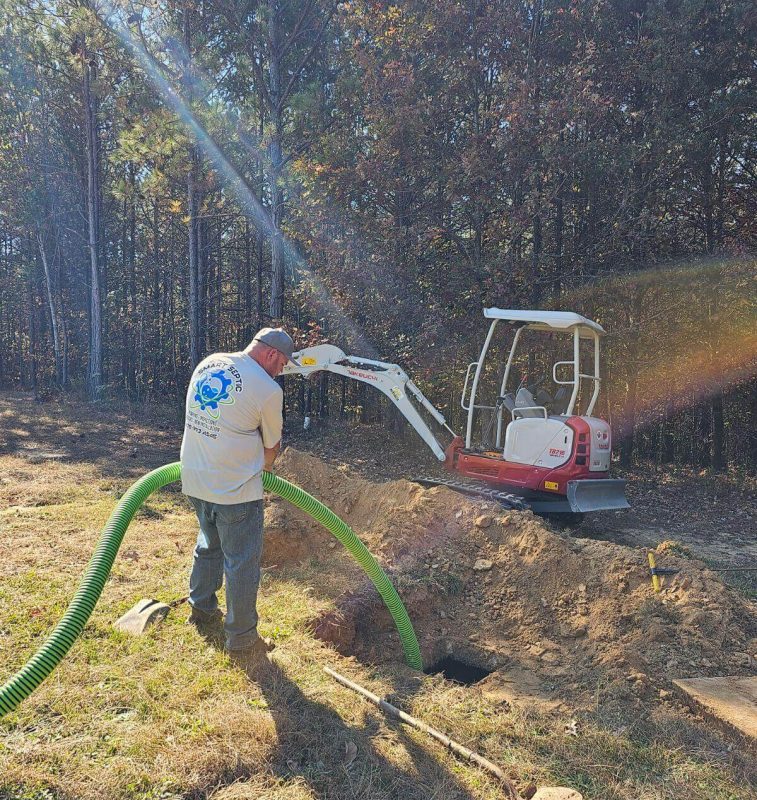 A man working on a tractor with a green hose.