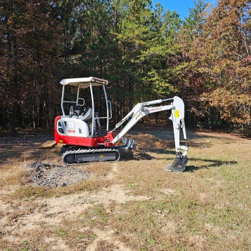 A red and white excavator in a field.